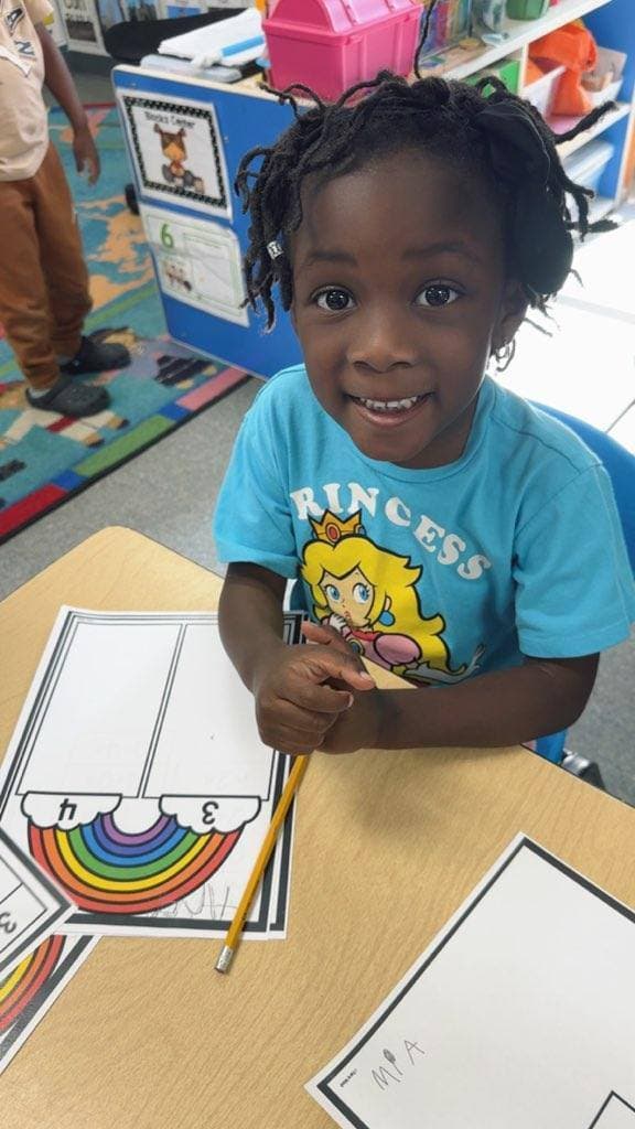A Falls Academy student smiling while working on a numbers worksheet